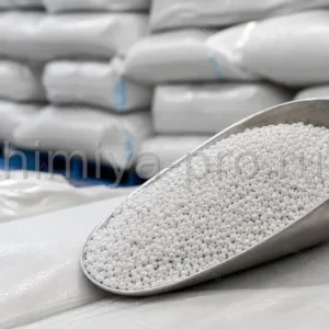 Белые и сероватые гранулы модификатора прочности для ПВХ в металлическом совке на фоне мешков с сырьём