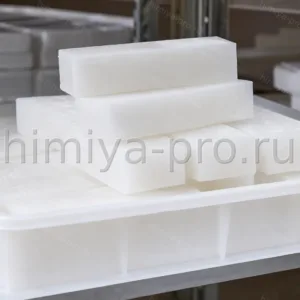 Белая восковая масса косметического церезина марки 75 в контейнере на складе декоративной косметики