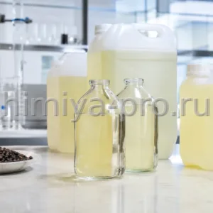 Бледно-жёлтое эфирное масло литсеи кубебы во флаконах и канистрах рядом с ягодами на каменном столе
