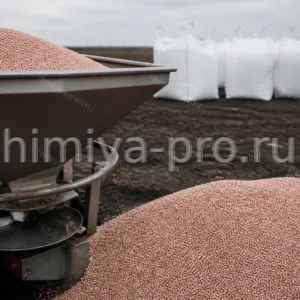 Розовато-жёлтые гранулы азотно-серного удобрения в бункере разбрасывателя на поле — сульфонитрат гранулированный NS 30:7