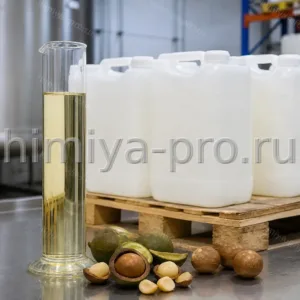 Бледно-жёлтое масло макадамии в стеклянном цилиндре рядом с промышленными канистрами на паллете